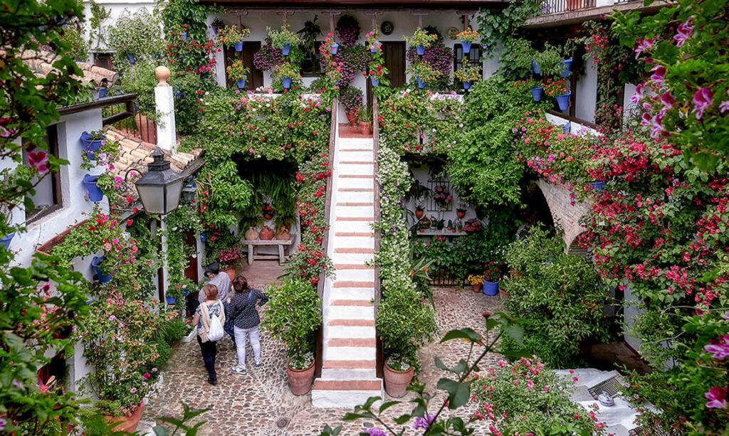 Un hermoso patio adornado con flores, banderas de Andalucía y elementos típicos, listo para celebrar el Día de Andalucía con alegría y colorido.